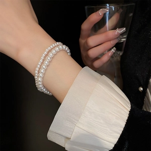 Close-up of elegant double-layered white pearl elastic bracelet worn on woman's wrist