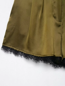 Detail der olivgrünen Satin-Shorts mit schwarzer Spitze und glatter Stoffstruktur