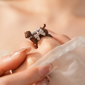 Detailed close-up of a brown dachshund ring featuring a sparkling silver bow tie