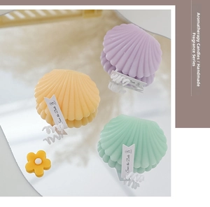 Detailed view of handmade shell-shaped scented candles in pastel yellow, purple, and mint green