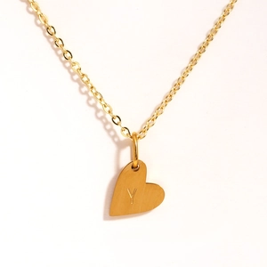 Vue macro d'un collier avec pendentif cœur doré et lettre Y gravée sur fond blanc pur