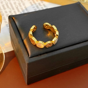 Détail de la bague dorée ajustable avec pierre œil-de-chat et motifs de pièces