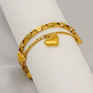 Détail d'un bracelet double couche doré avec trois délicats pendentifs en cœur