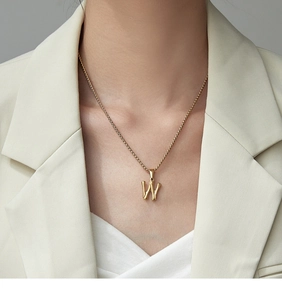 Detail of a 18K gold plated bamboo style letter W pendant on a minimalist chain