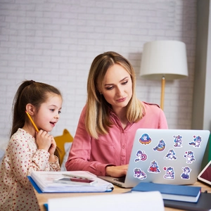Girl and mother playing with cute waterproof unicorn cartoon stickers on table surface