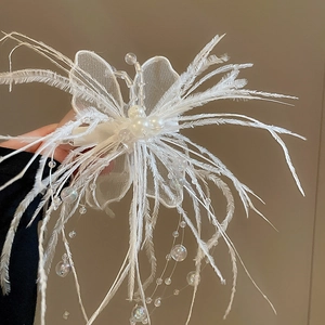 Détail de la pince à cheveux papillon blanche avec plumes, perles et glands perlés