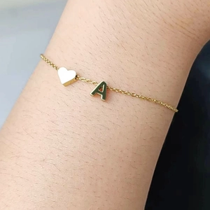 Detail shot of a minimalist gold O-chain bracelet featuring a heart and letter A charm