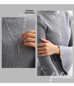 Detail of elegant gold and silver bar necklaces styled on a grey knit sweater