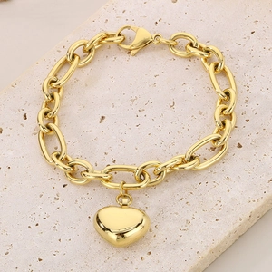 Dettaglio del bracciale a catena ovale dorata con ciondolo a cuore su pietra