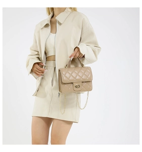 Detail of a beige quilted chain bag featuring a gold twist lock and elegant texture