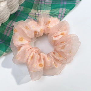 Close-up of pink tulle scrunchie with yellow floral patterns and soft ruffled texture