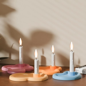 Flower shaped candle holder set in pastel colors on dark wood table with plant shadows