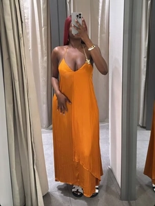 Dettaglio dell'abito in raso arancione con elegante catena metallica dorata sullo scollo