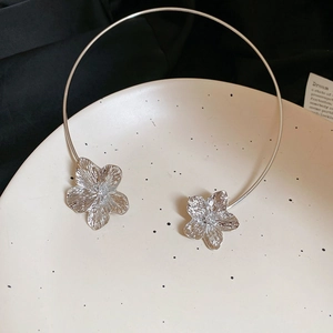 Macro detail of silver metal flower choker with hammered texture on a white plate