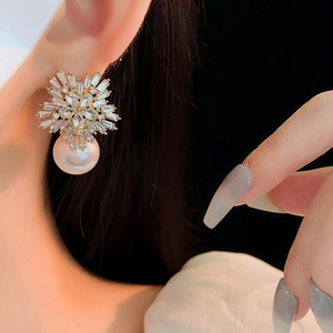 Macro shot of gold floral earrings with crystal rhinestones and large dangling pearls