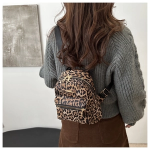 Rear view of a model wearing the leopard print mini backpack with adjustable straps