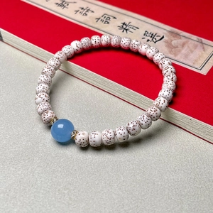 Detail of Xingyue Bodhi seed bracelet with blue agate bead on a poetry book