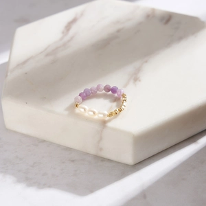 Macro shot of bohemian ring with purple amethyst beads and freshwater pearls on marble