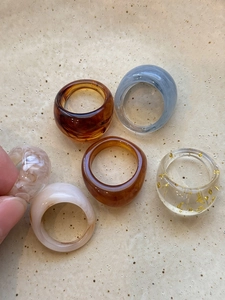 Flat lay of multiple tortoiseshell resin rings in amber and grey on ceramic plate