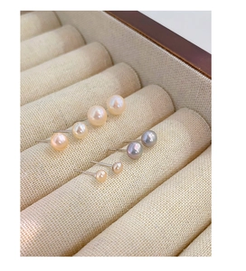 Detailed view of three pairs of multi-sized natural freshwater pearl studs in beige and gray