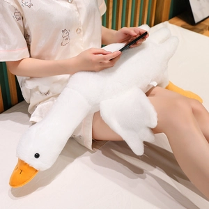 Cozy lifestyle scene showing a model holding a large white goose plush pillow on a soft bed