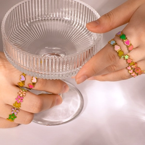 Farbenfrohe Emaille-Ringe mit Herz und Blumen aus Edelstahl an der Hand des Models