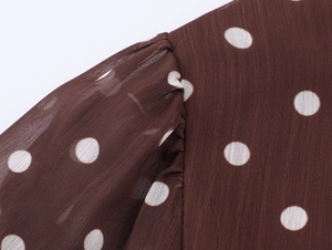 Dettaglio delle cuciture delle maniche a sbuffo su abito in chiffon marrone a pois