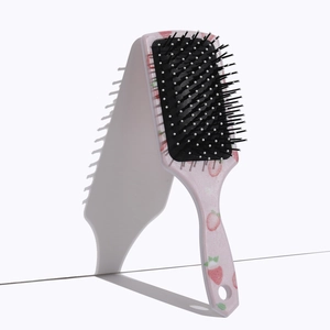 Detail of square air cushion hairbrush with pink strawberry print handle and black bristles