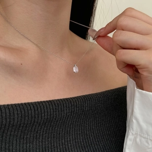 Detail of a square pink gemstone necklace on a model wearing grey knitwear