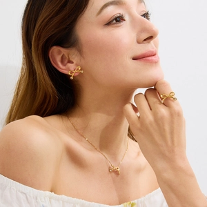 Détail d'un mannequin portant une parure de bijoux nœud doré avec cristaux blancs
