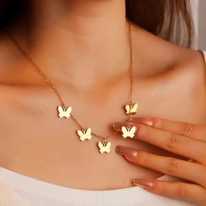Close-up of five delicate gold butterfly pendants on a minimalist women's choker necklace