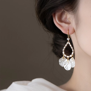Boucles d'oreilles dorées avec diamants et pampilles de pétales blancs sur un mannequin