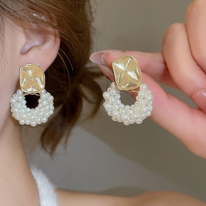 Detail showing elegant gold stud earring with clustered white pearls on a female model