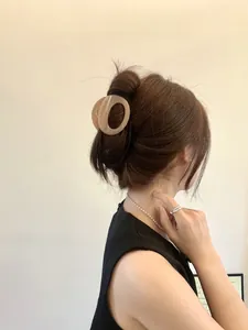 Detailed view of an oval apricot hair claw clip securing a chic updo bun for women