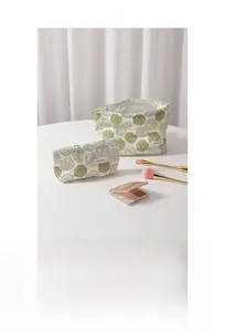 Close-up of white cotton linen makeup bag set featuring green botanical leaf embroidery
