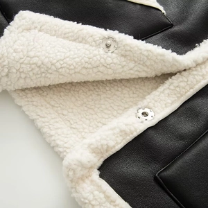 Detalle de chaleco de cuero sintético negro con forro de lana crema y botones metálicos