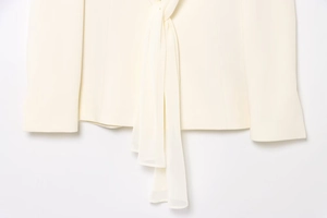 Détail du col écharpe crème avec un design élégant à nouer sur le blazer chic