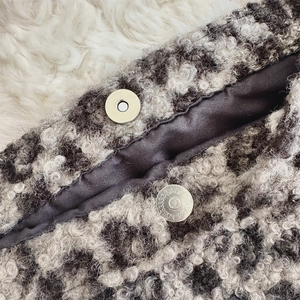 Detailed macro view of the fluffy leopard faux shearling fabric and silver magnetic closure