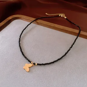 Gold plated black bead heart necklace with a butterfly pendant on a velvet background