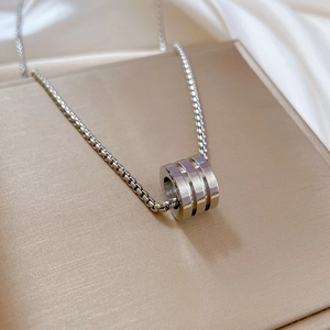 Close-up of silver titanium steel cylinder pendant on a gift box with silk background
