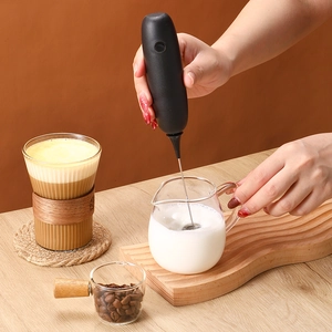 Handheld electric milk frother in black for coffee foam preparation in a home setting