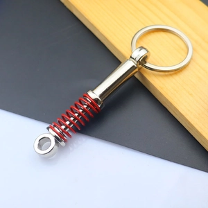 Detail of metal car shock absorber keychain with red spring on wood background