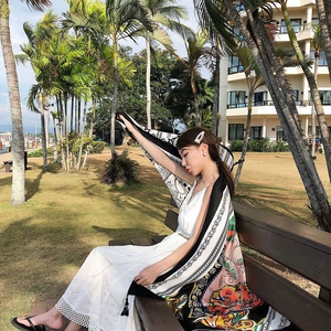 Detailed view of long ethnic silk scarf with tassels worn with a white summer dress
