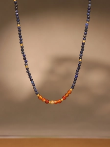 Vue détaillée du collier en perles de lapis-lazuli et agate rouge avec perles dorées