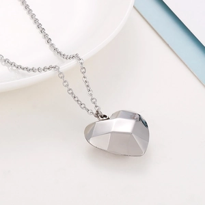 Collier avec pendentif cœur géométrique 3D argenté et chaîne fine sur surface blanche