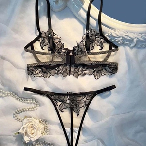 Sexy black lace floral embroidery mesh bra and thong set on white silk background