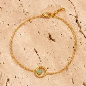 Detail of 18K gold-plated bracelet with green natural stone on beige stone texture