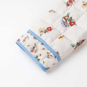 Close-up of quilted floral sleeve detail with blue piped edges and clean white background