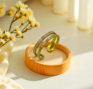 Detail of adjustable gold ring with white enamel inlay and polished metal finish