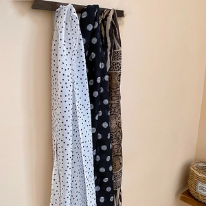 Close-up of elegant polka dot and geometric animal print chiffon scarf necklaces on a stand